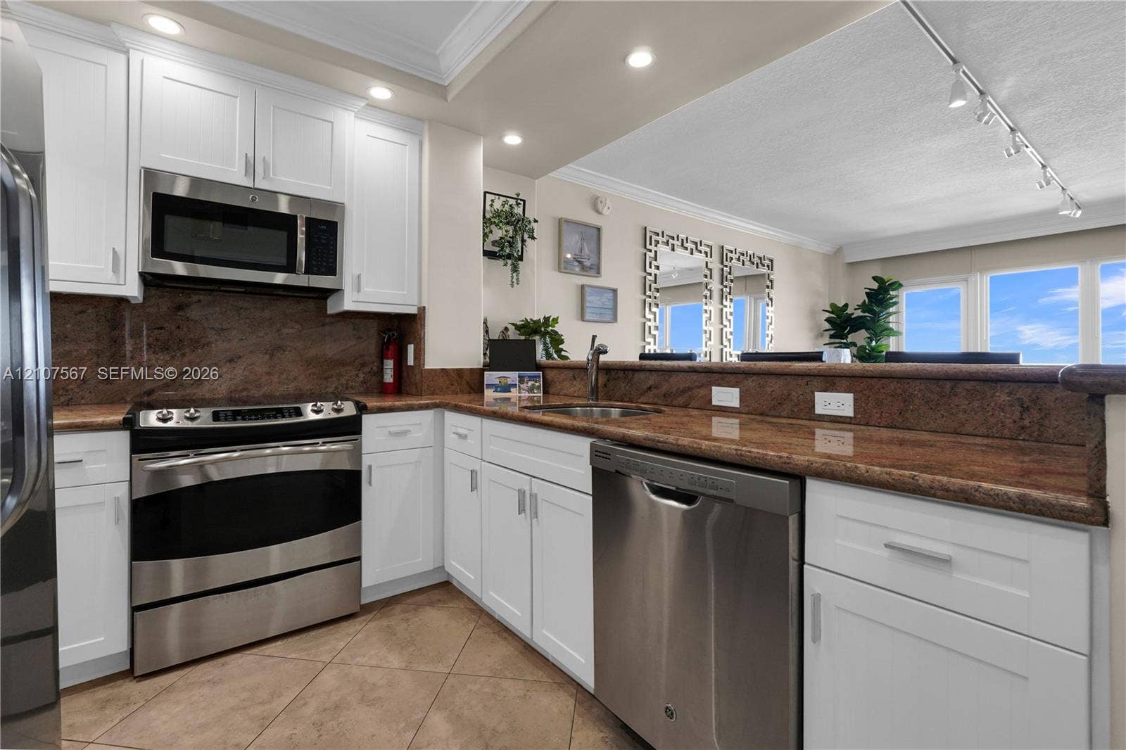 Kitchen featuring white cabinetry, stone countertops, stone backsplash, stainless steel appliances, and tile flooring