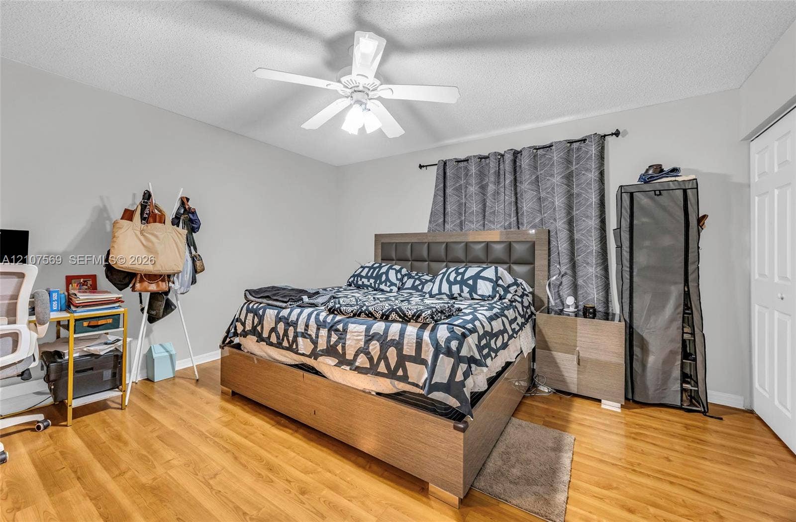 3765 San Simeon Circle, #3765, Weston, Weston, FL 33331 Bedroom featuring wood-finish flooring, a white six-panel closet door, and a white ceiling fan with integrated lighting