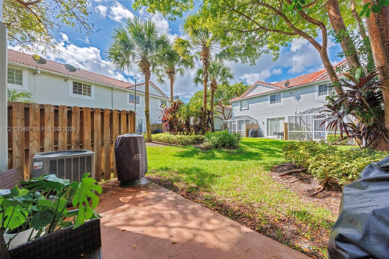 3765 San Simeon Circle, #3765, Weston, Weston, FL 33331 Rear outdoor space featuring a paved patio, wood privacy fencing, mature palm trees, and manicured green space