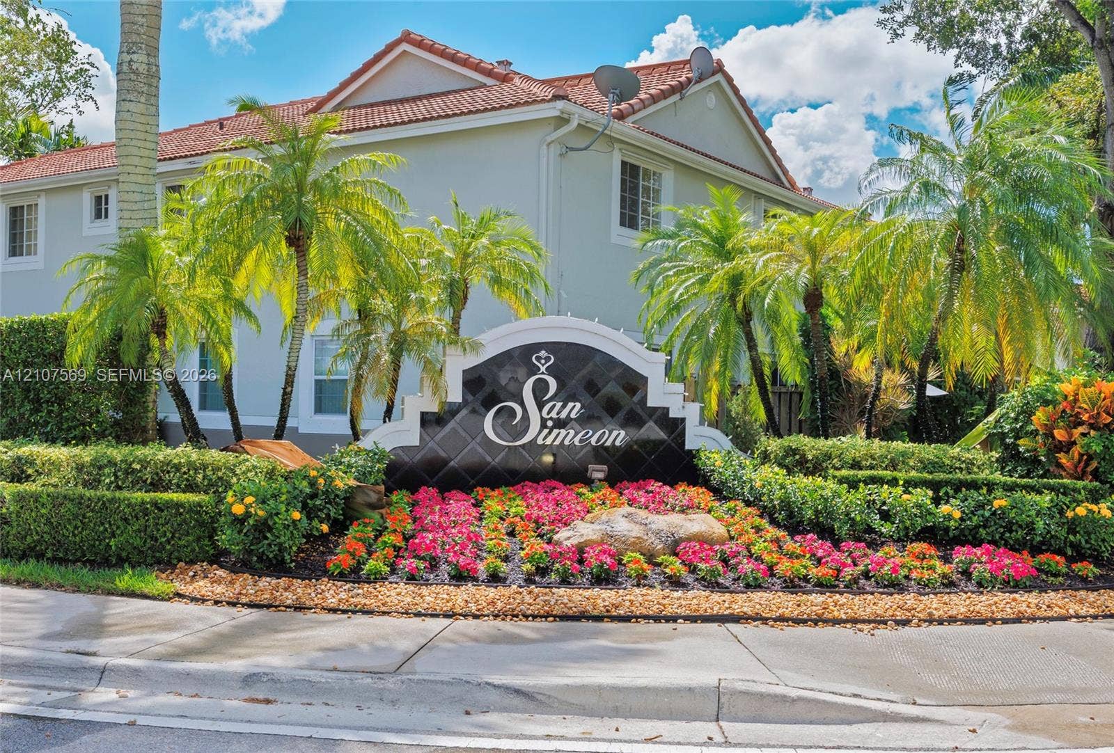 3765 San Simeon Circle, #3765, Weston, Weston, FL 33331 Stucco exterior with a tile roof, complemented by a professional monument sign and manicured landscaping featuring flowering shrubs and palm trees