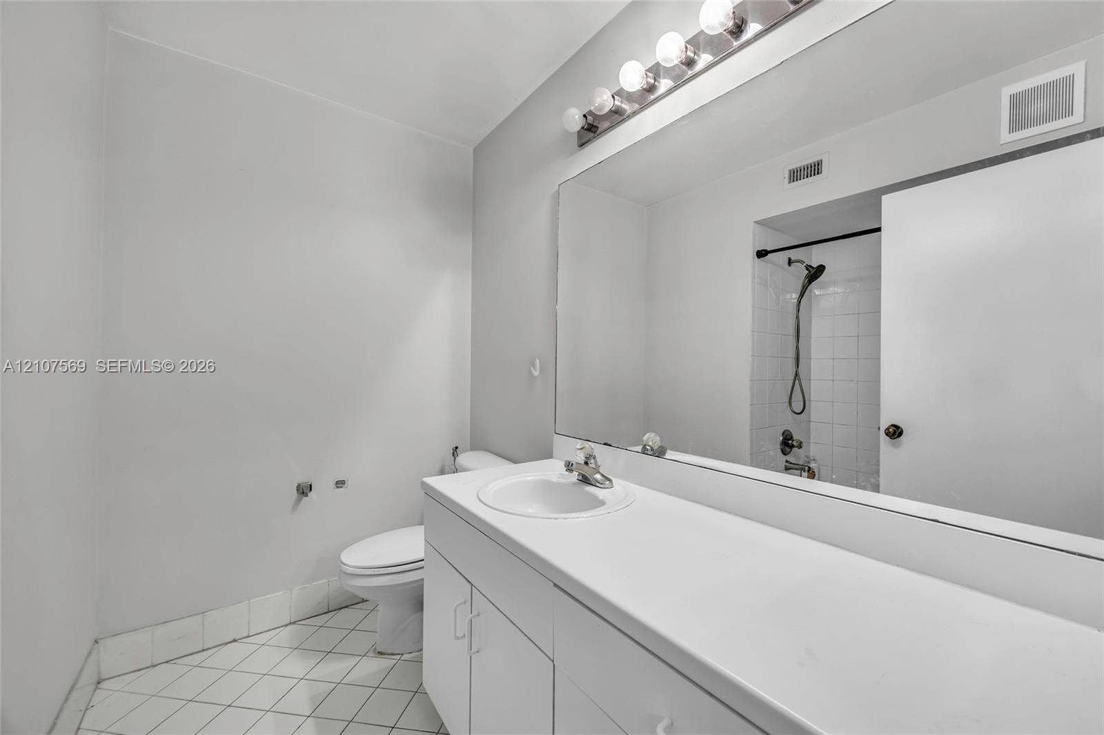 3765 San Simeon Circle, #3765, Weston, Weston, FL 33331 Bathroom featuring a white vanity with a solid-surface countertop, an expansive wall-to-wall mirror, an integrated sink with a chrome faucet, and tile flooring