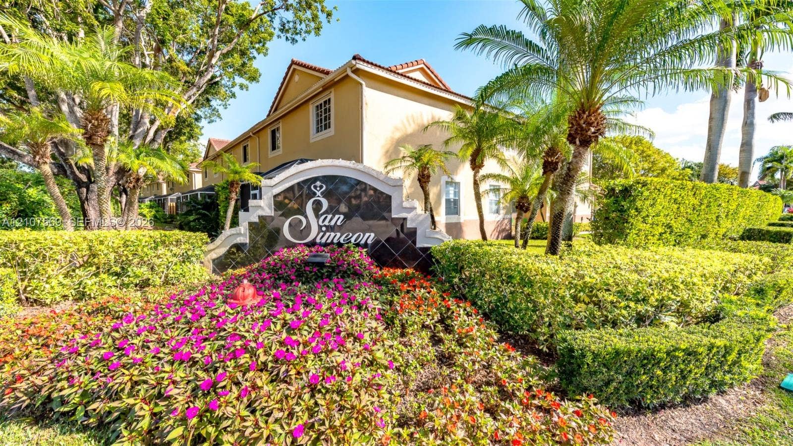 3765 San Simeon Circle, #3765, Weston, Weston, FL 33331 Community entrance featuring professional landscaping with manicured hedges, mature palm trees, floral beds, and custom masonry signage