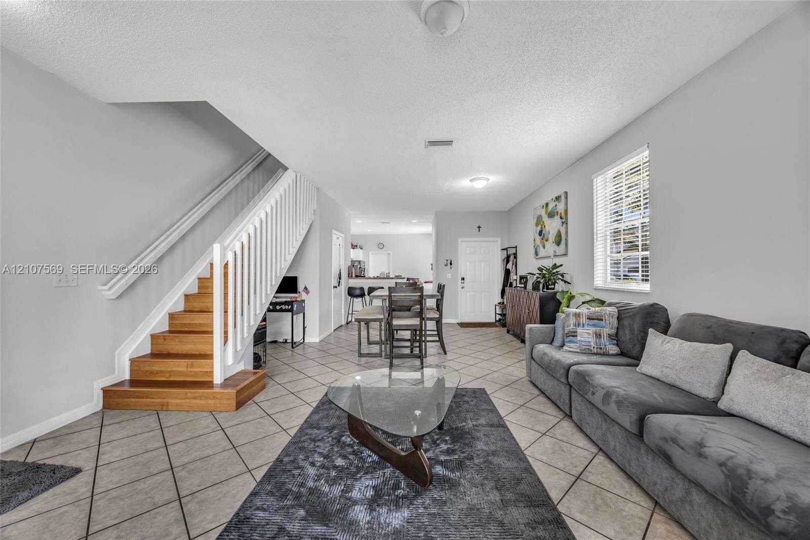 3765 San Simeon Circle, #3765, Weston, Weston, FL 33331 Open-concept interior featuring large-format tile flooring, a staircase with wood treads, and white vertical balusters