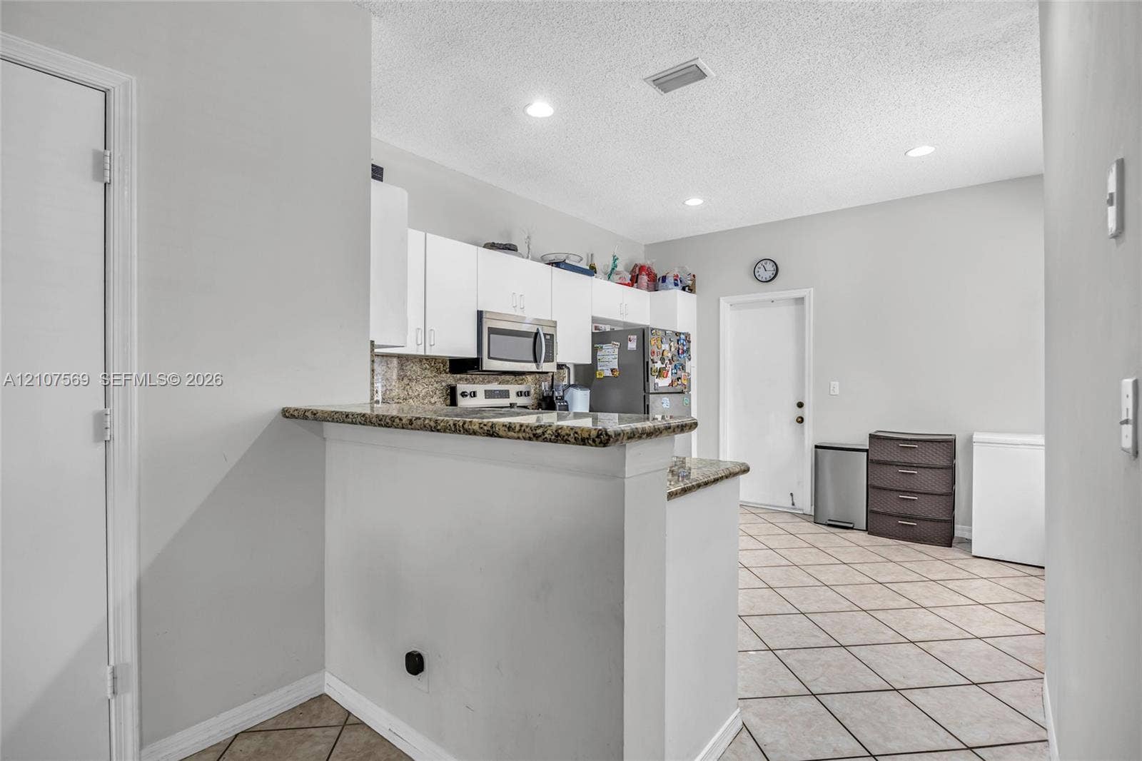 3765 San Simeon Circle, #3765, Weston, Weston, FL 33331 Kitchen featuring white cabinetry, stone-surface countertops, tile flooring, recessed lighting, and a breakfast bar
