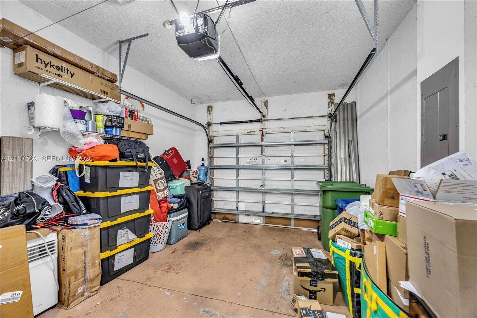 3765 San Simeon Circle, #3765, Weston, Weston, FL 33331 Enclosed garage featuring a sectional metal overhead door, concrete flooring, and an integrated electrical service panel