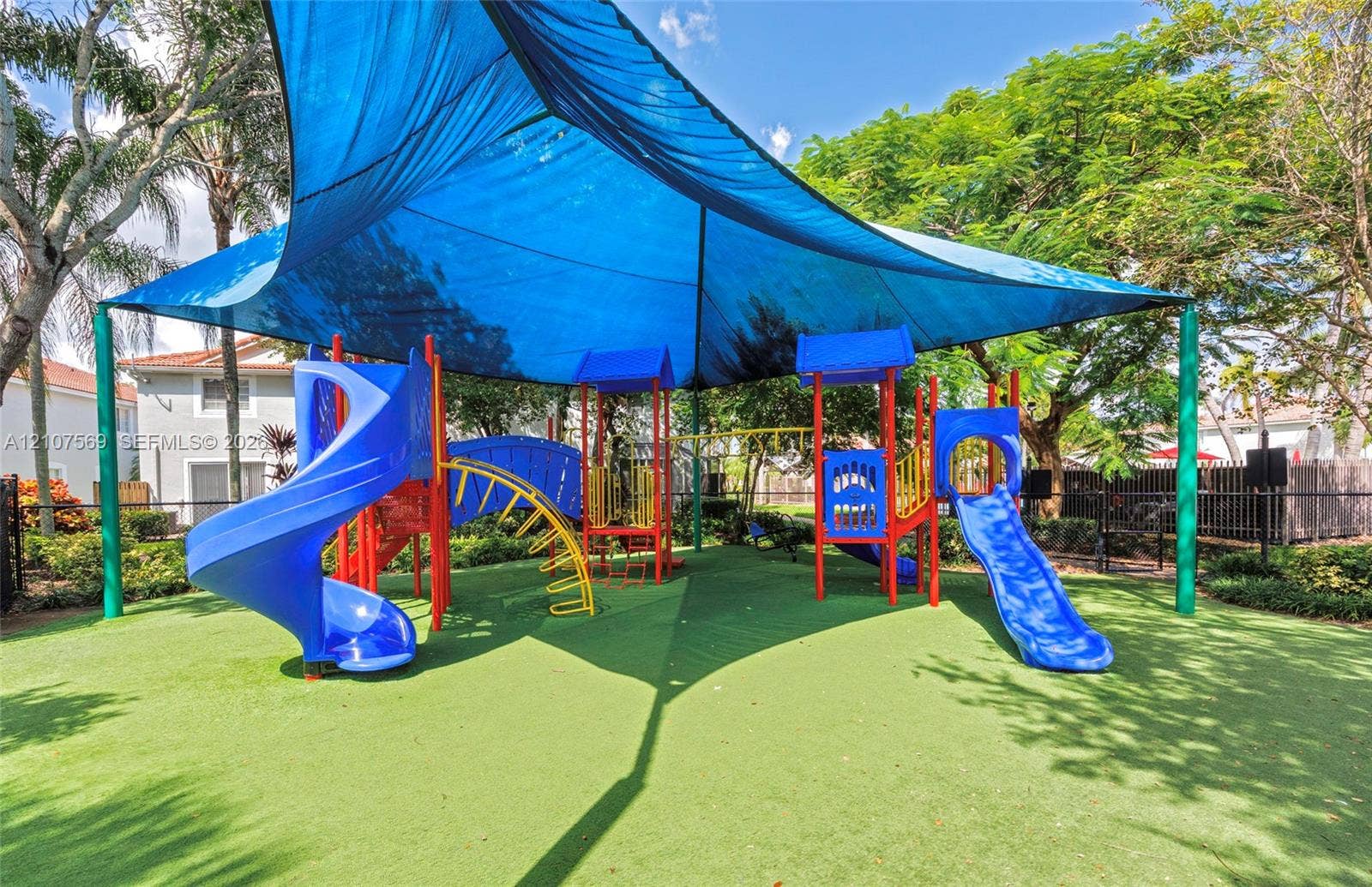 3765 San Simeon Circle, #3765, Weston, Weston, FL 33331 Recreational area featuring a multi-component play structure with dual slides and overhead shade canopy set atop synthetic turf