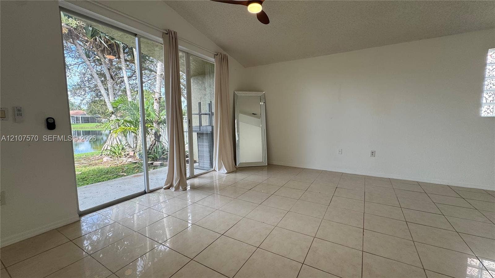 Sliding glass doors featuring ceramic tile flooring, a vaulted ceiling, a ceiling fan with integrated lighting, and glass block accent windows