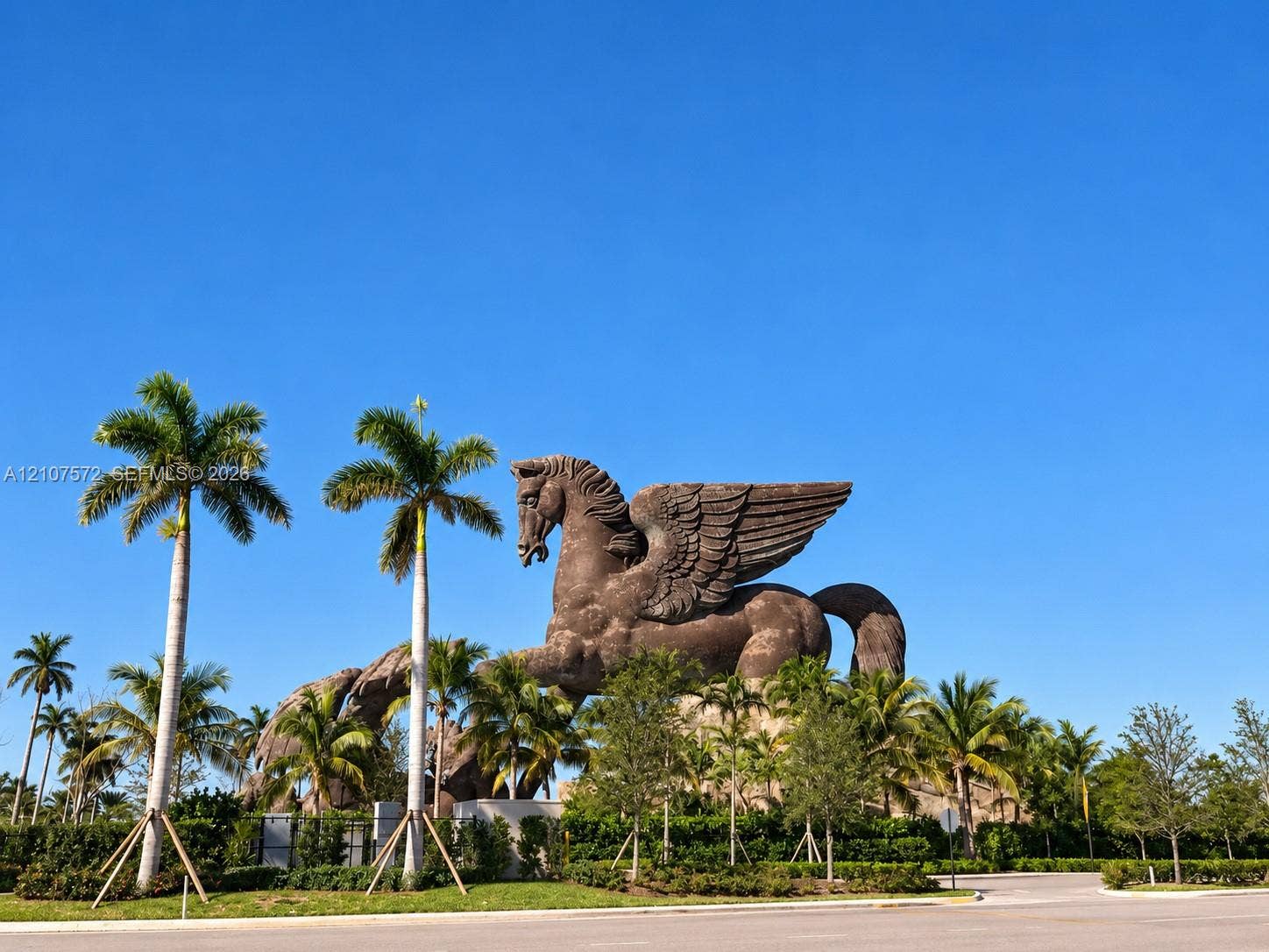 1425 Atlantic Shores Boulevard, #501, Hallandale Beach, FL 33009 Large-scale winged horse sculpture featuring detailed stone-textured masonry, set within a landscaped perimeter of mature palm trees and manicured vegetation