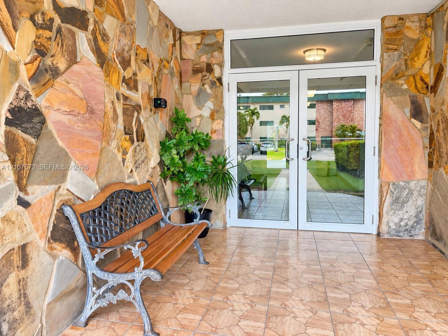 1425 Atlantic Shores Boulevard, #501, Hallandale Beach, FL 33009 Entryway featuring natural stone veneer walls, ceramic tile flooring, and a double-door glass entrance with transom window