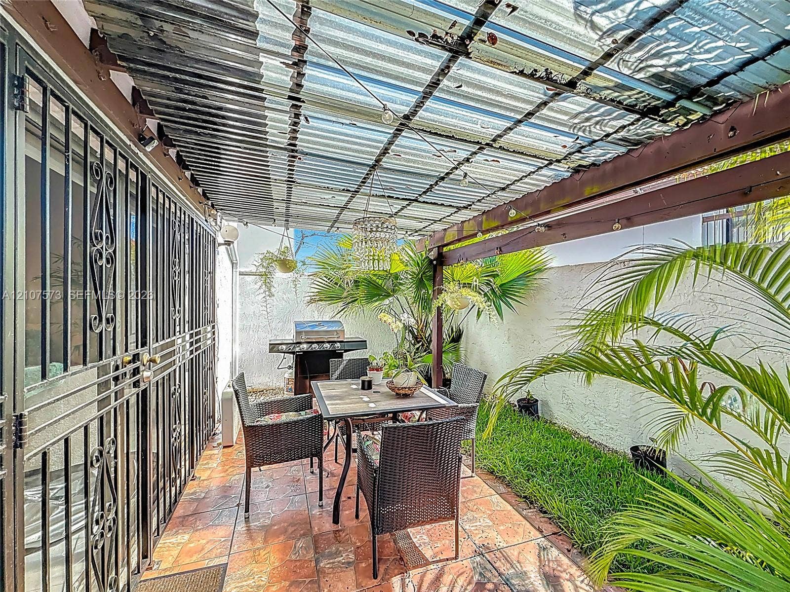 1291 SW 124th Court, #19-B, Miami, FL 33184 Enclosed patio featuring decorative metal security doors, tile flooring, and a privacy wall
