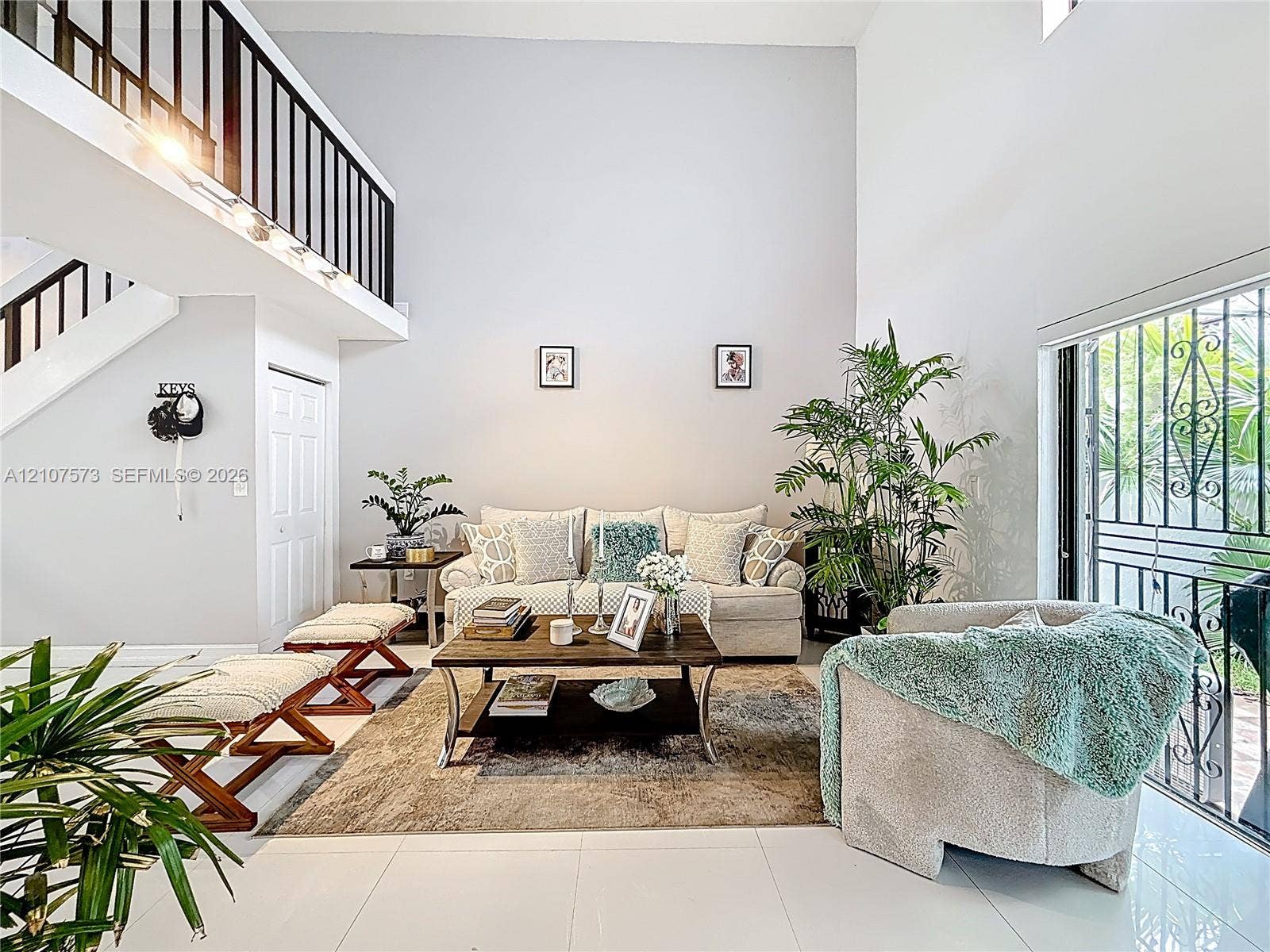 1291 SW 124th Court, #19-B, Miami, FL 33184 Living room featuring soaring double-height ceilings, ceramic tile flooring, and a mezzanine level with black balusters