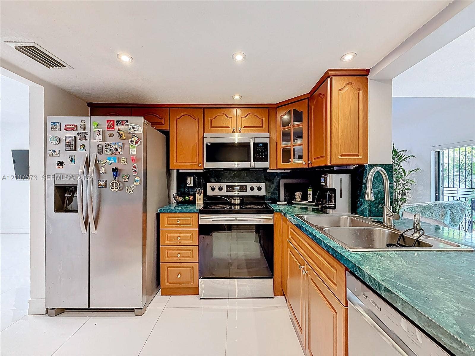 1291 SW 124th Court, #19-B, Miami, FL 33184 Kitchen featuring medium-tone wood cabinetry, green stone countertops, stainless steel appliances, and recessed lighting
