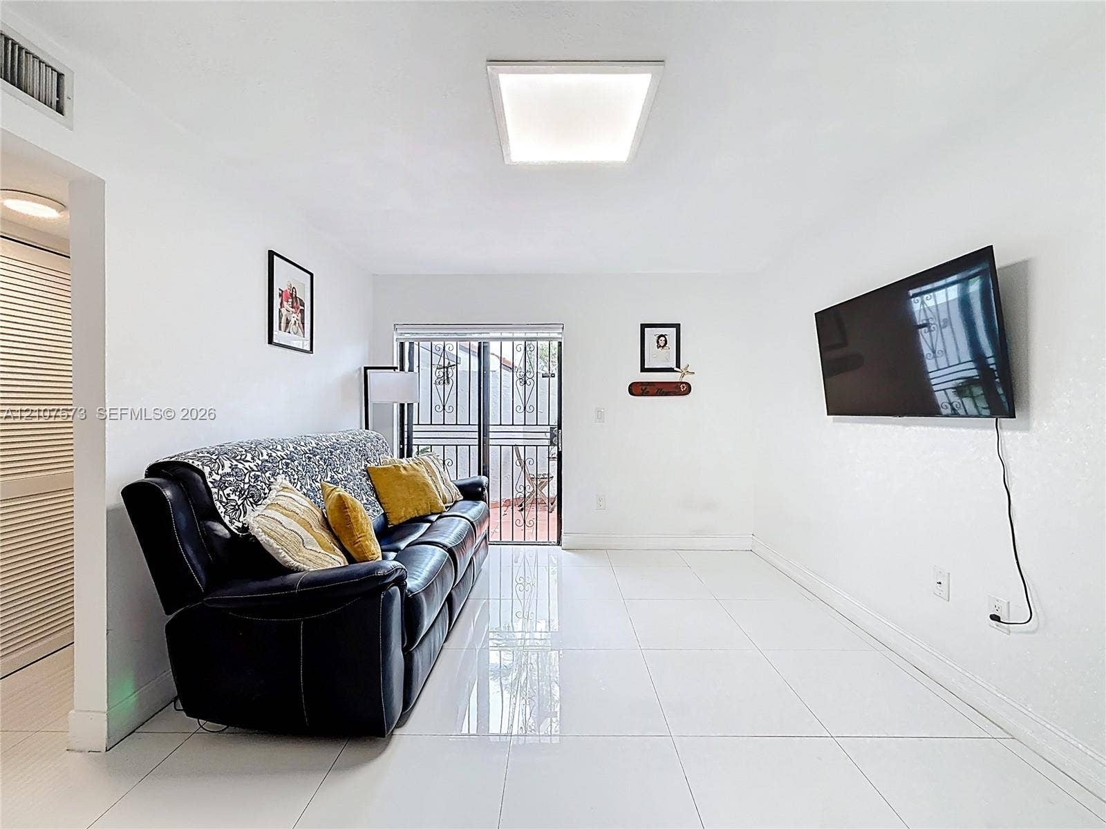 1291 SW 124th Court, #19-B, Miami, FL 33184 Living area featuring polished tile flooring, flush-mount lighting, and glass sliding doors with decorative metal security bars