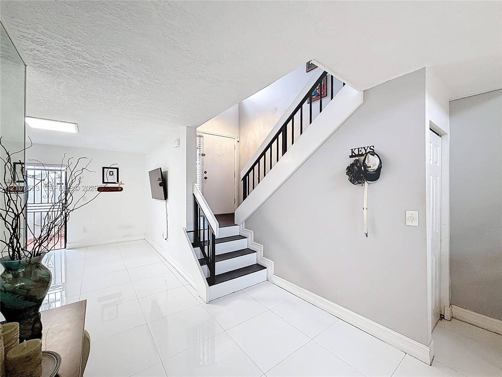 1291 SW 124th Court, #19-B, Miami, FL 33184 Staircase featuring black-painted treads, white risers, and a metal balustrade, complemented by polished white tile flooring