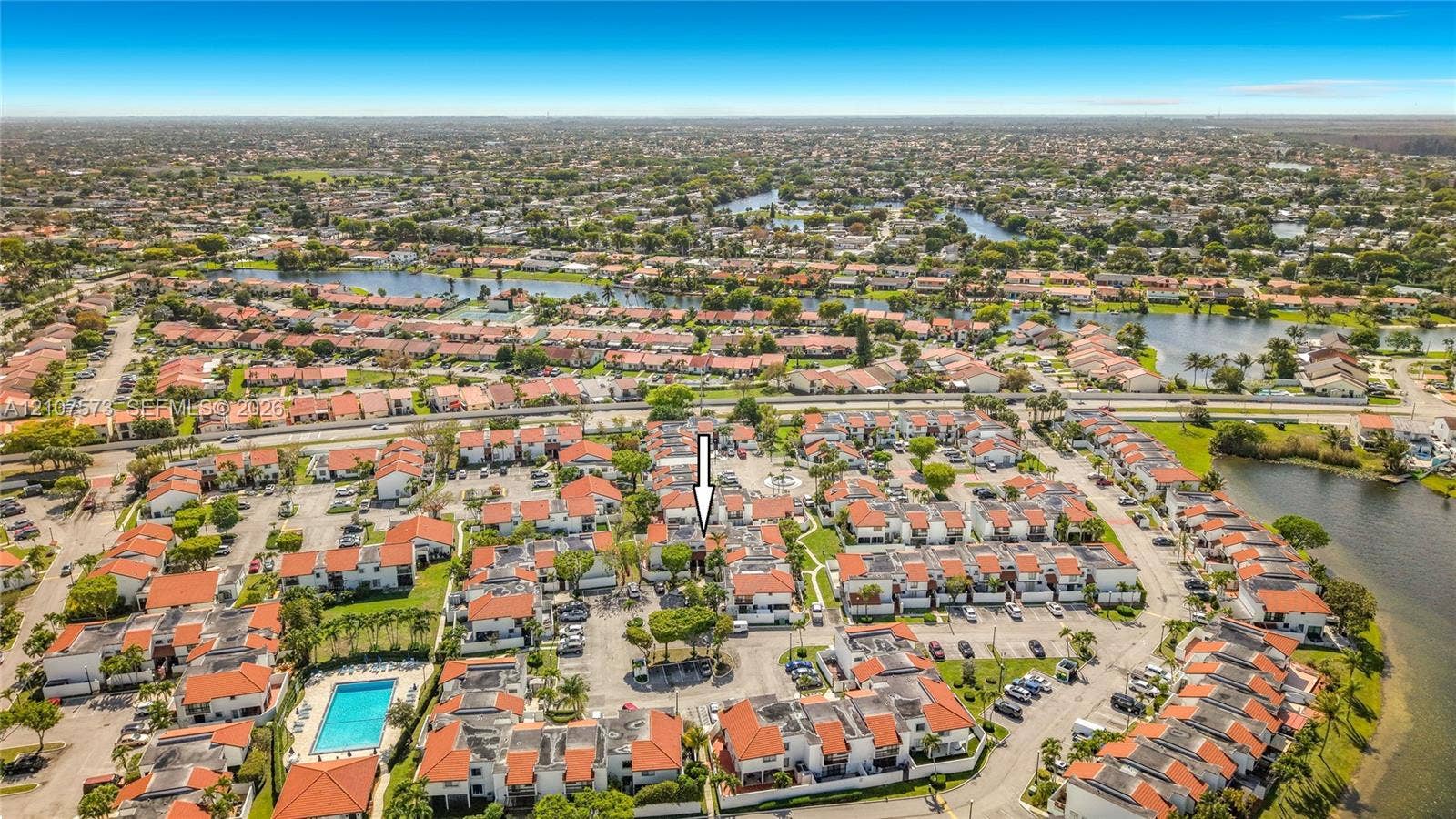 1291 SW 124th Court, #19-B, Miami, FL 33184 Aerial perspective of a multi-unit residential community featuring red tile roofs, stucco exterior finishes, and proximity to community water features and a swimming pool