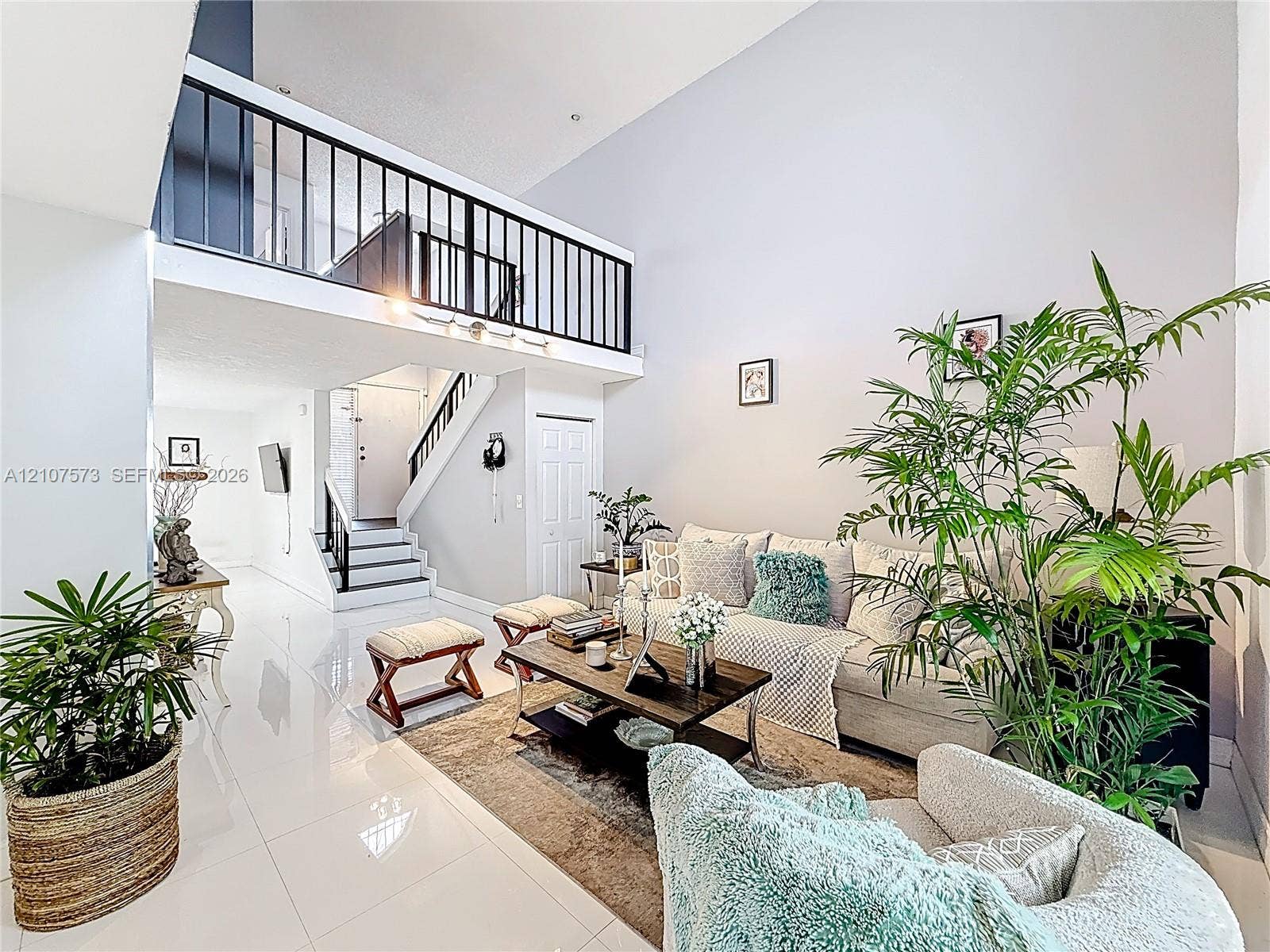1291 SW 124th Court, #19-B, Miami, FL 33184 Double-height ceiling, polished tile flooring, and a metal-railed mezzanine overlooking the space, complemented by a central staircase with metal railings