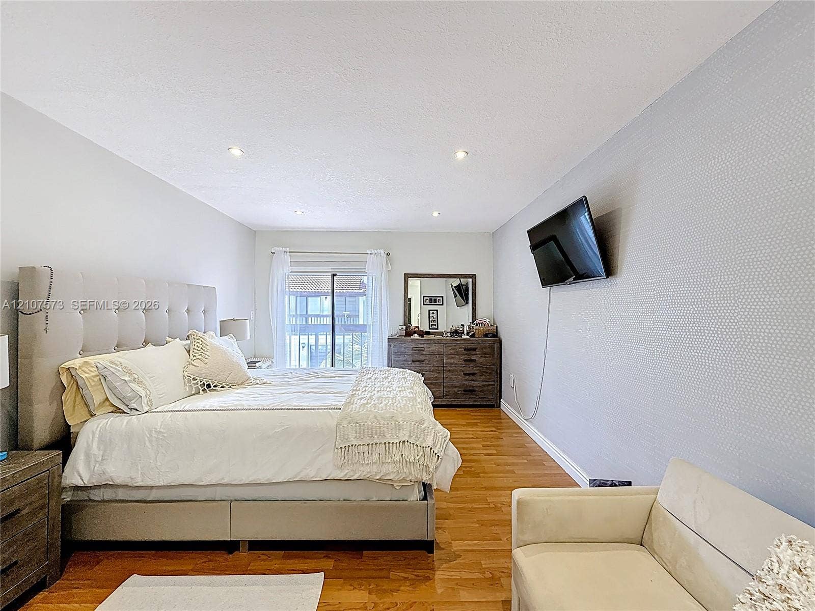 1291 SW 124th Court, #19-B, Miami, FL 33184 Interior space featuring wood-finish flooring, recessed lighting, and a textured accent wall with sliding glass door access to an exterior balcony