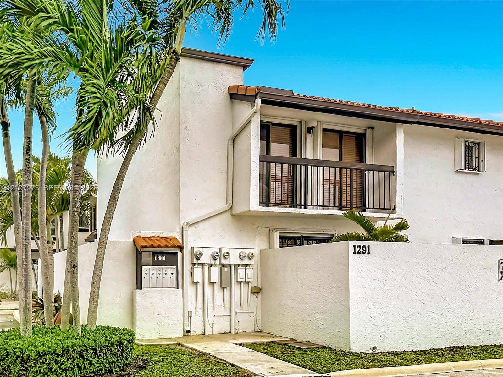 1291 SW 124th Court, #19-B, Miami, FL 33184 Two-story exterior featuring white stucco finish, tile roof accents, metal balcony railing, and concrete perimeter wall