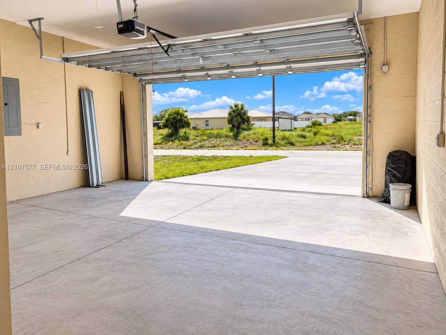 Attached garage featuring painted concrete masonry unit walls, a concrete floor, and an automated overhead door