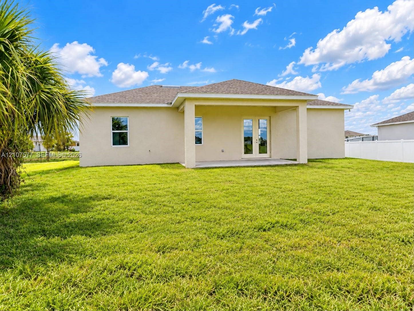 Stucco exterior featuring a covered rear patio, dual-pane glass entry doors, and a vinyl privacy fence