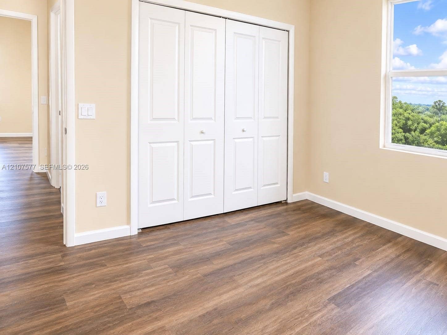 Wood-finish flooring, white paneled bi-fold closet doors, and single-pane window