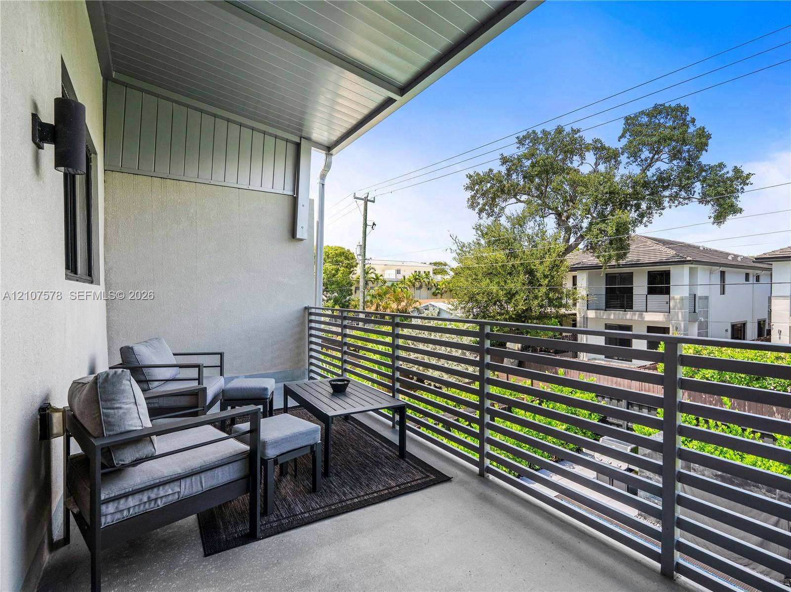 307 SW 10th Street, Fort Lauderdale, FL 33315 Covered balcony featuring concrete flooring, horizontal metal railing, and wall-mounted exterior lighting