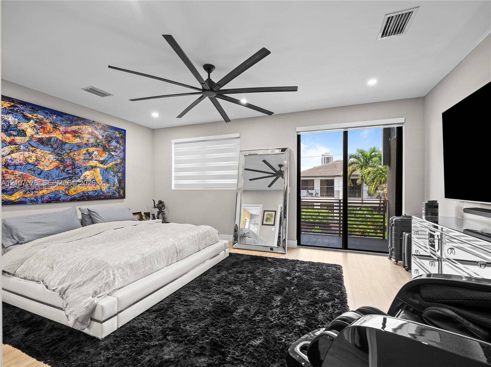 307 SW 10th Street, Fort Lauderdale, FL 33315 Expansive room featuring recessed lighting, a multi-blade matte black ceiling fan, wood-finish flooring, and a large sliding glass door providing access to a private balcony