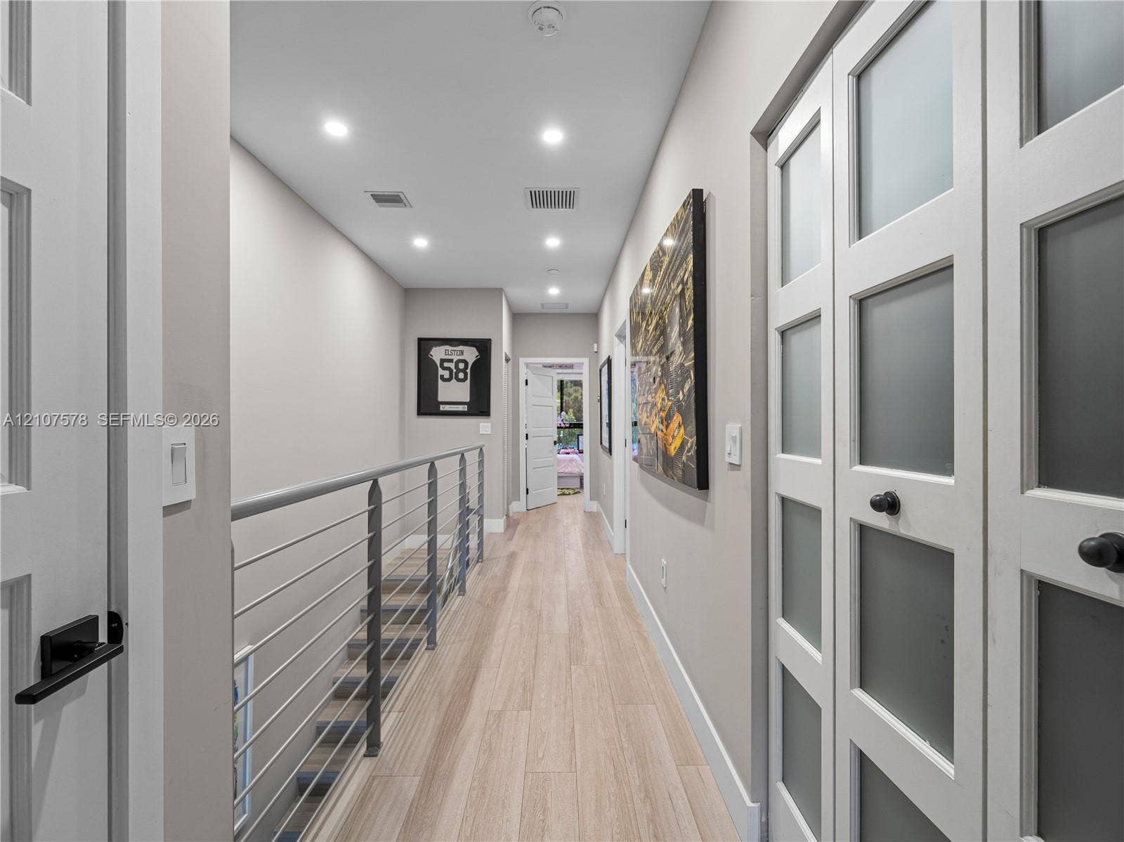 307 SW 10th Street, Fort Lauderdale, FL 33315 Hallway featuring wood-finish flooring, recessed lighting, double doors with frosted glass panels, and a metal horizontal-bar railing