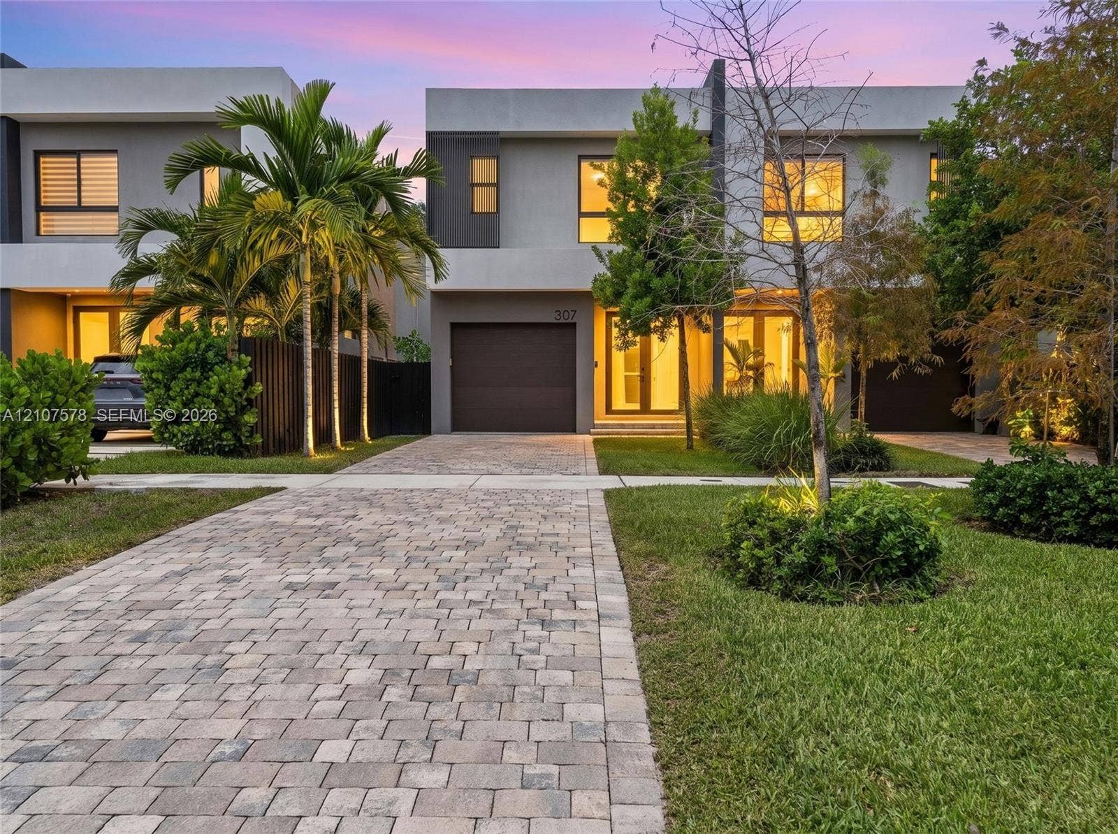 307 SW 10th Street, Fort Lauderdale, FL 33315 Modern architectural exterior featuring a concrete facade, paver driveway, integrated garage, and floor-to-ceiling glass entry doors