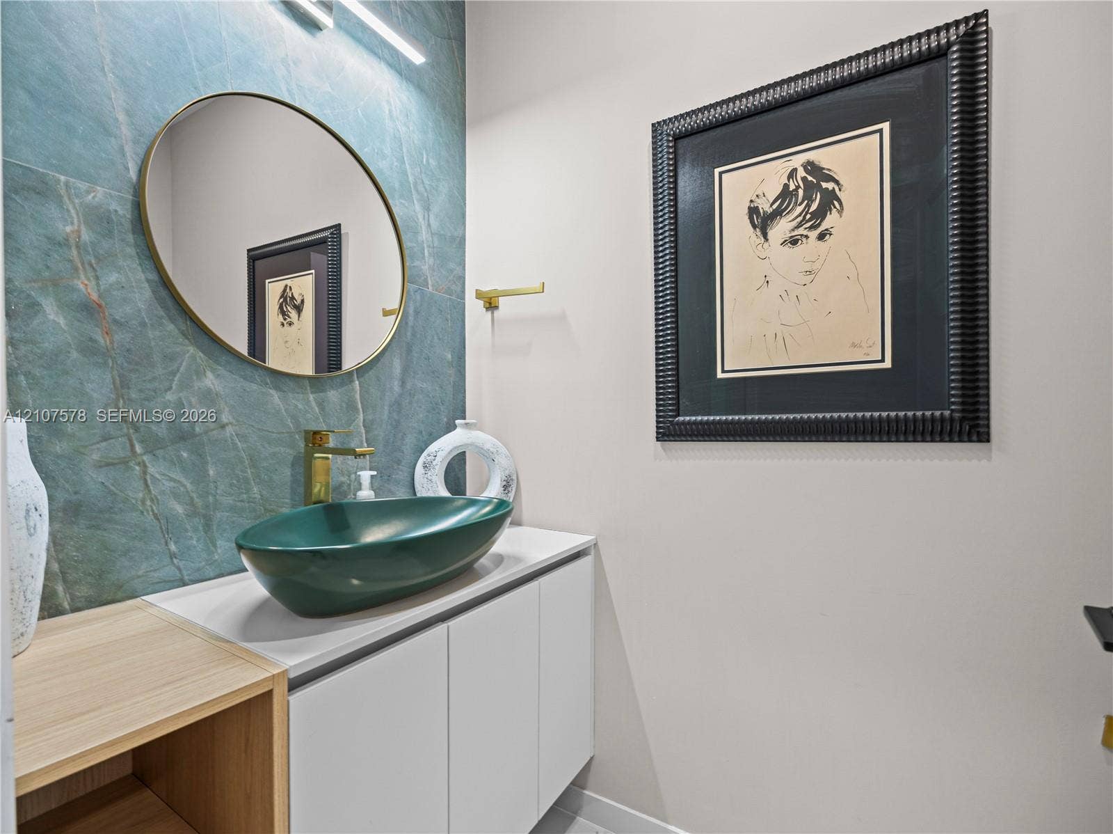307 SW 10th Street, Fort Lauderdale, FL 33315 Floating vanity with white cabinetry and wood-finish shelving, topped with a green vessel sink, gold-tone faucet, and large-format teal tile backsplash featuring an oval mirror and minimalist linear lighting