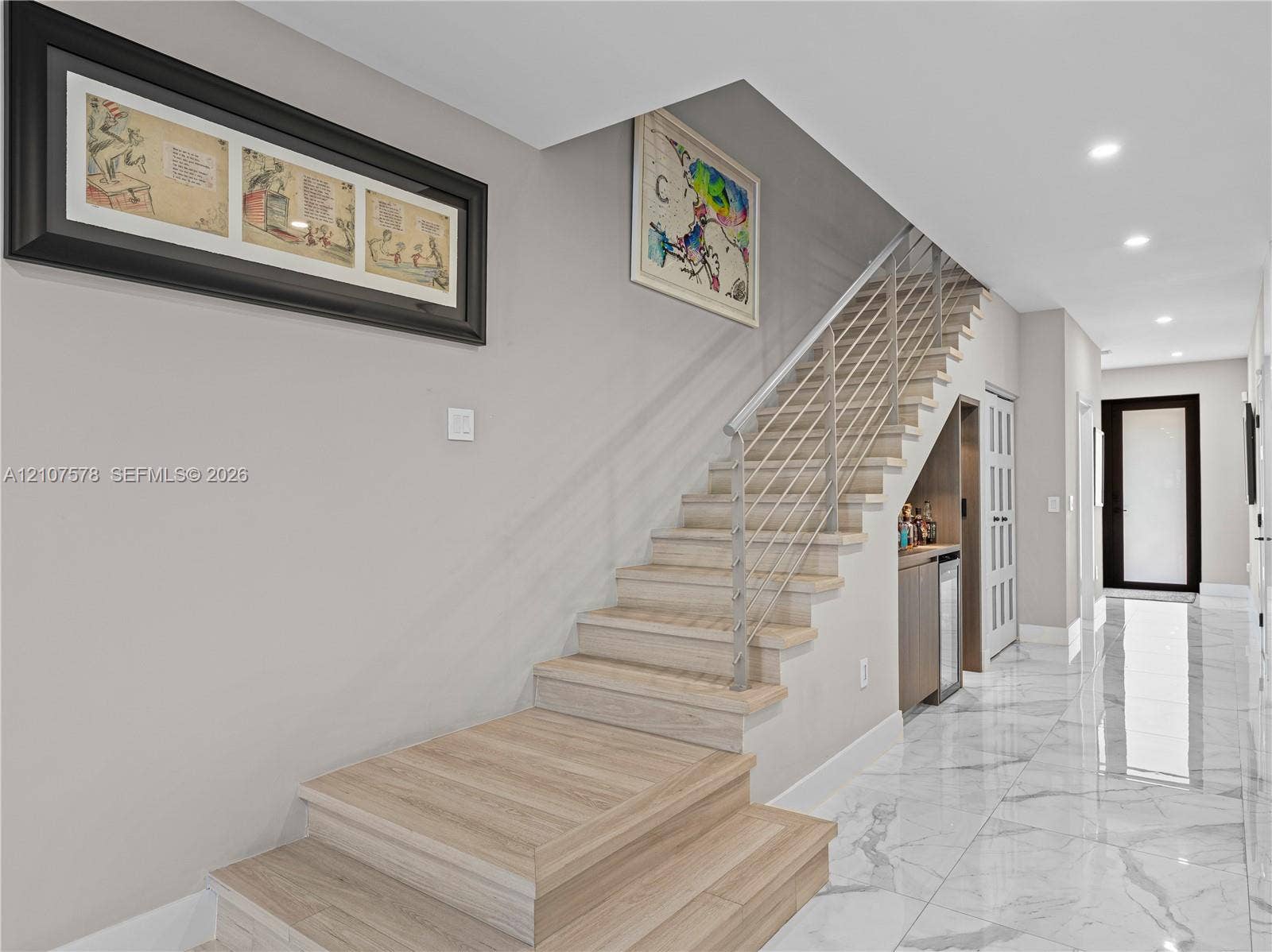 307 SW 10th Street, Fort Lauderdale, FL 33315 Staircase featuring wood-finish treads, metal horizontal railing, light-toned stone-finish flooring, recessed ceiling lighting, and built-in under-stair wet bar cabinetry
