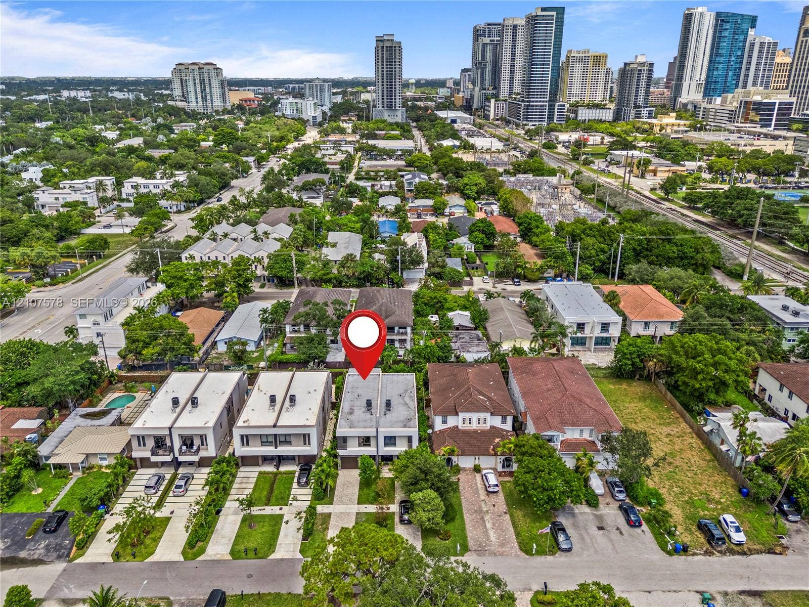 307 SW 10th Street, Fort Lauderdale, FL 33315 Aerial perspective showcasing a multi-level residential structure with a flat roof, integrated garage, concrete-paved driveway, and proximity to high-rise metropolitan infrastructure