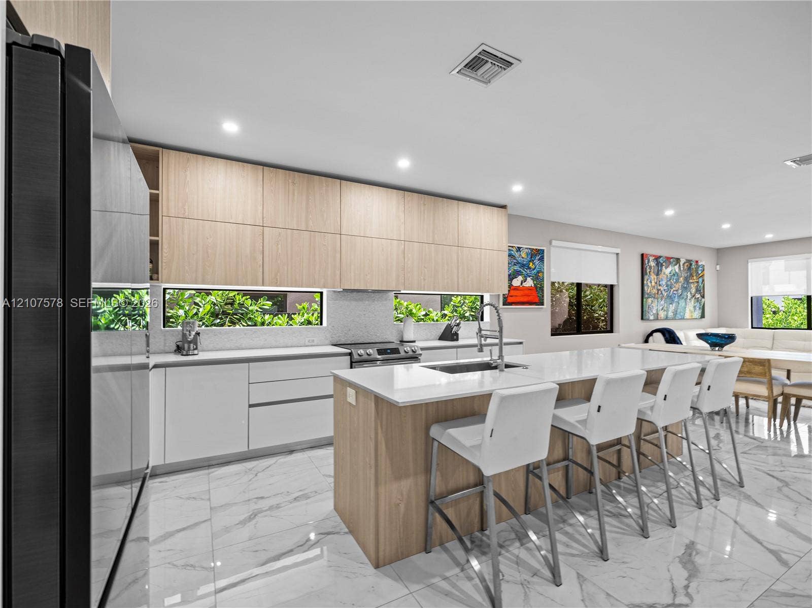 307 SW 10th Street, Fort Lauderdale, FL 33315 Kitchen featuring flat-panel wood and white cabinetry, stone-finish countertops, a central island with an integrated sink, and light-toned tile flooring