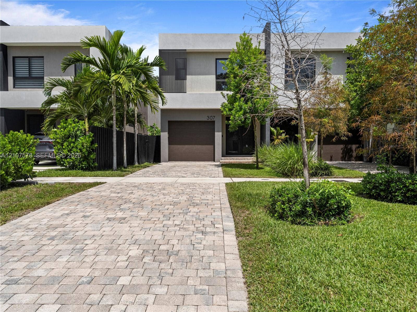 307 SW 10th Street, Fort Lauderdale, FL 33315 Contemporary two-story exterior featuring a smooth stucco facade, paver driveway, and an integrated single-car garage