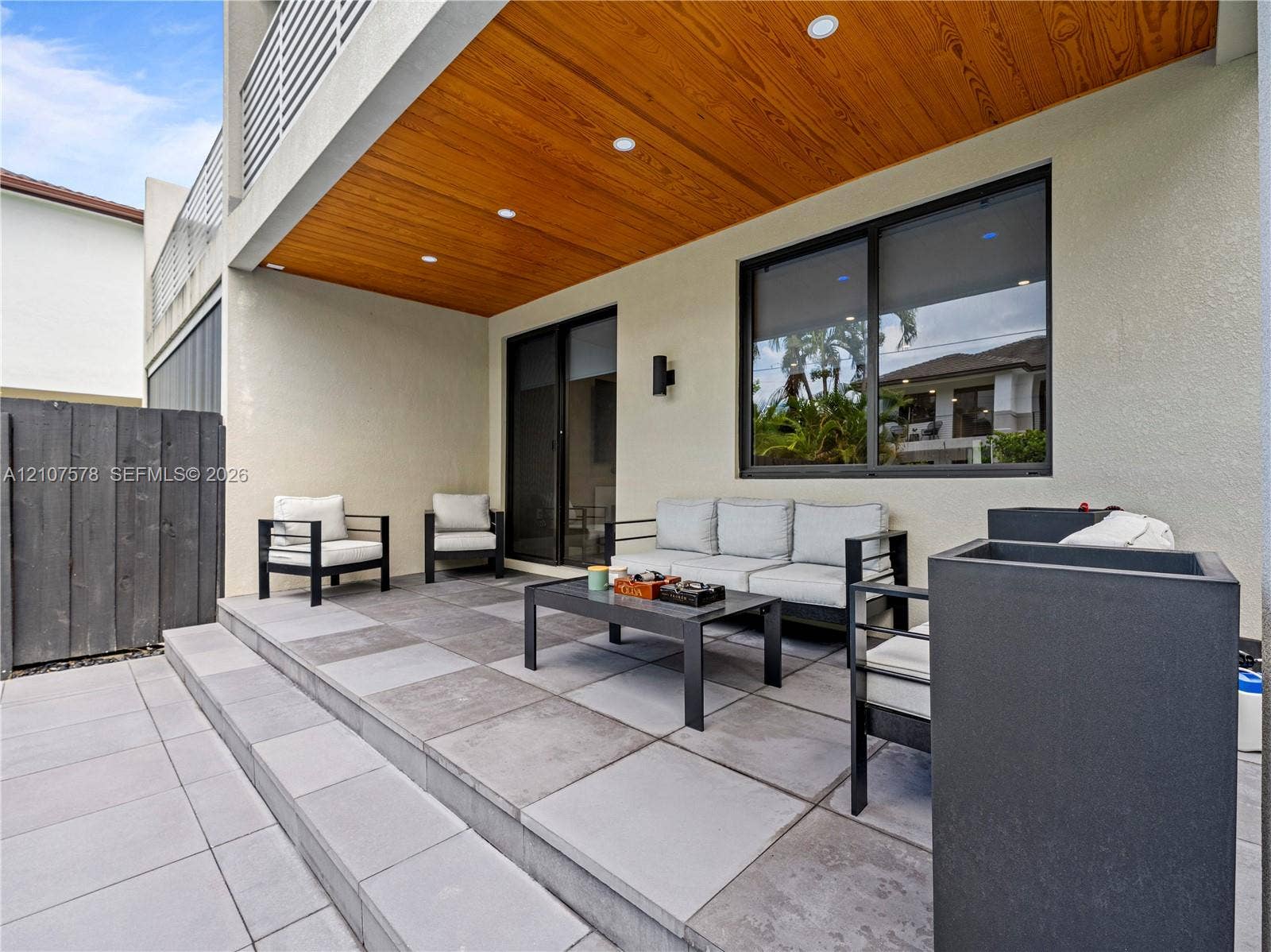 307 SW 10th Street, Fort Lauderdale, FL 33315 Covered patio featuring a wood-panel ceiling, recessed lighting, large-format tile flooring, and integrated black-framed windows and sliding glass doors