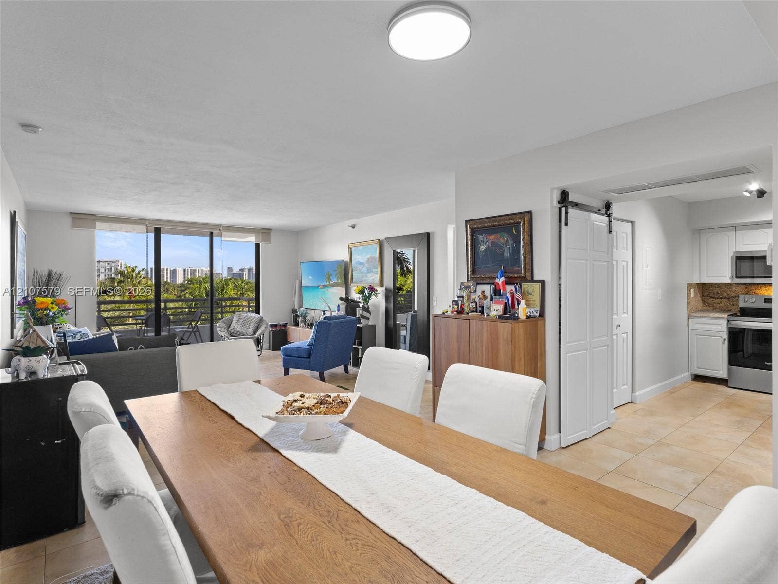 3300 NE 191st Street, #511, Aventura, FL 33180 Interior featuring tile flooring, a white sliding barn door, and a full-height glass balcony enclosure