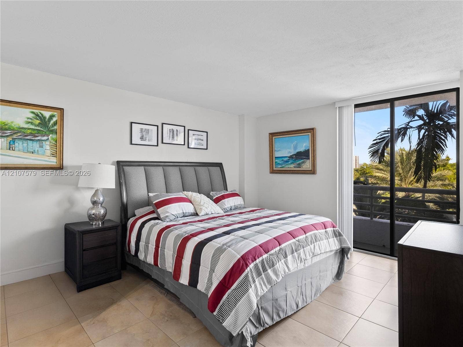 3300 NE 191st Street, #511, Aventura, FL 33180 Neutral-toned tile flooring, large sliding glass door with access to a private balcony, and palm tree scenery