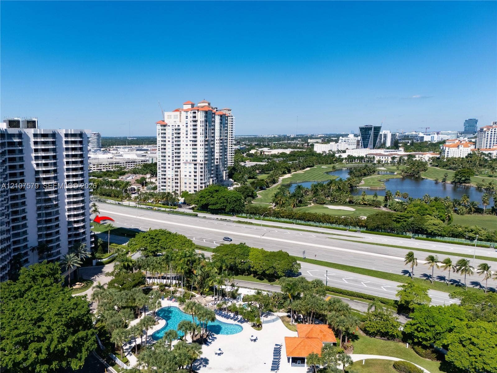 3300 NE 191st Street, #511, Aventura, FL 33180 High-rise residential building featuring a swimming pool, paved sundeck, tropical landscaping, and proximity to green space