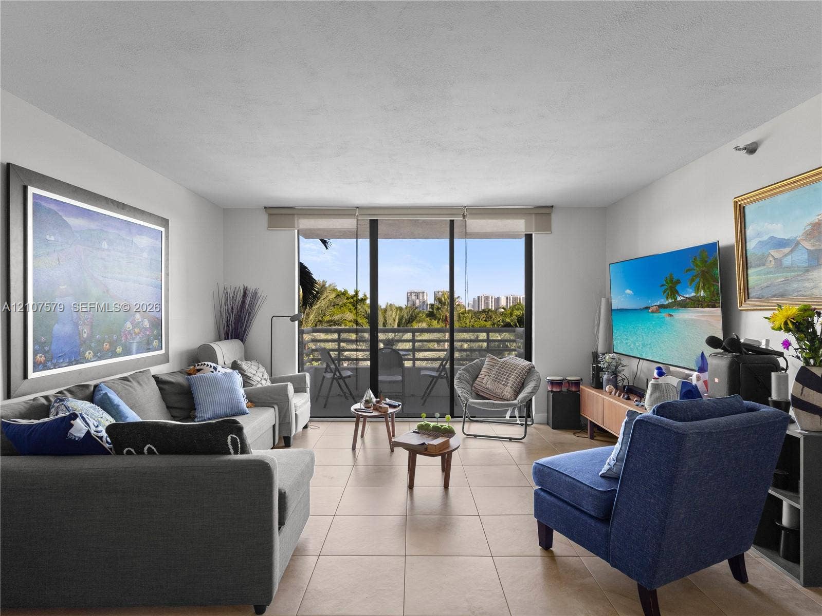 3300 NE 191st Street, #511, Aventura, FL 33180 Living area featuring neutral ceramic tile flooring and floor-to-ceiling sliding glass doors opening to a private balcony