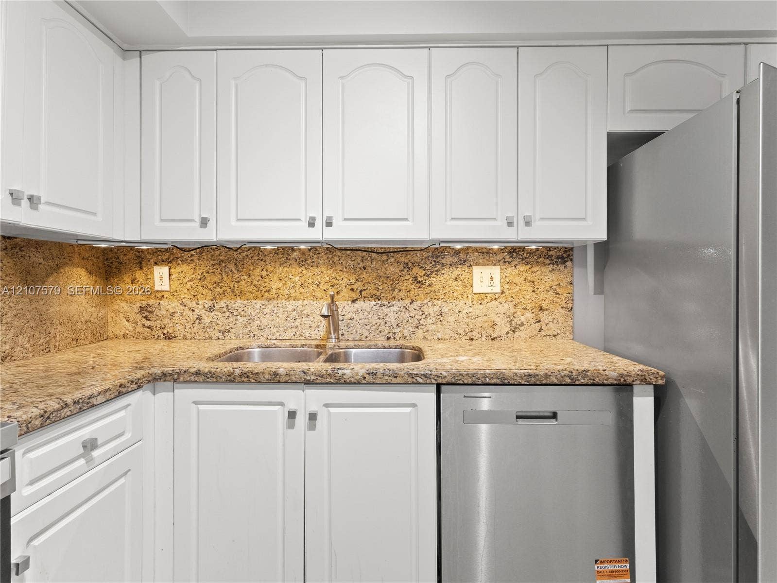 3300 NE 191st Street, #511, Aventura, FL 33180 Kitchen featuring white cabinetry, stone-surface countertops, full-height stone backsplash, stainless steel dishwasher, and under-cabinet lighting