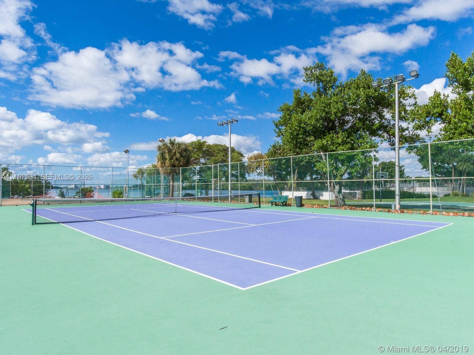 Tennis court with a blue playing surface and green surrounds