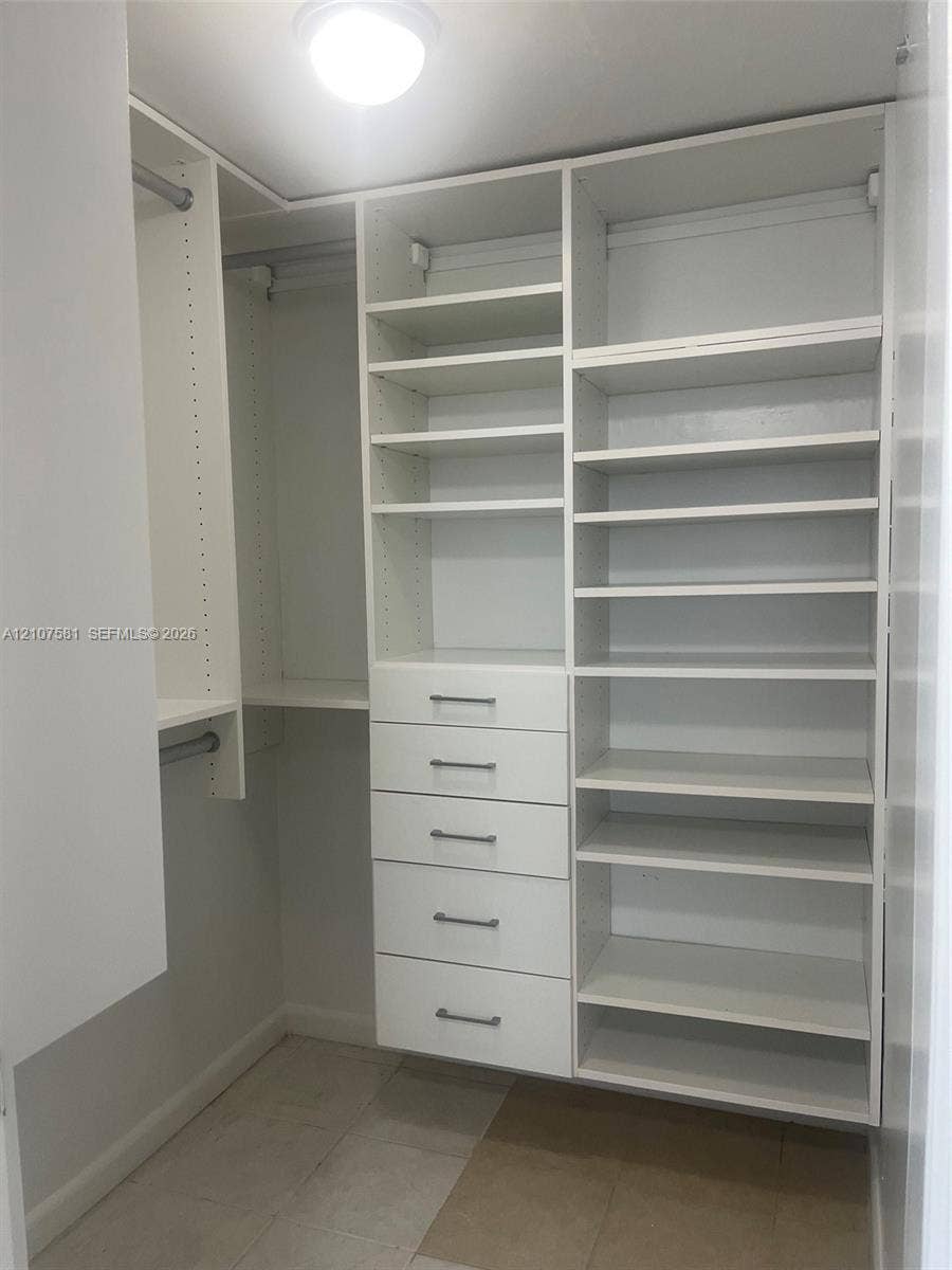 Custom built-in closet system featuring multiple shelving units, integrated drawers with linear pulls, and hanging rods