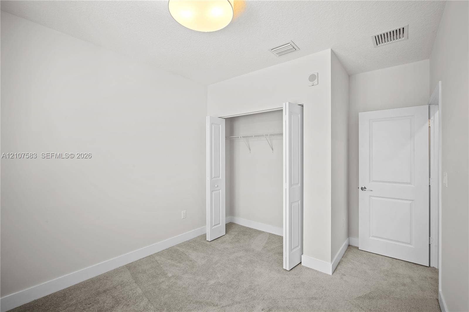 10270 NW 66th Street, #110, Doral, Doral, FL 33178 Neutral interior featuring neutral wall paint, carpeted flooring, a closet with bi-fold doors, and a paneled interior door