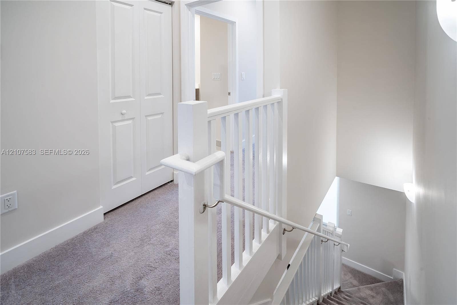 10270 NW 66th Street, #110, Doral, Doral, FL 33178 Staircase featuring a white wooden balustrade and handrail, carpeted flooring, and a multi-panel door