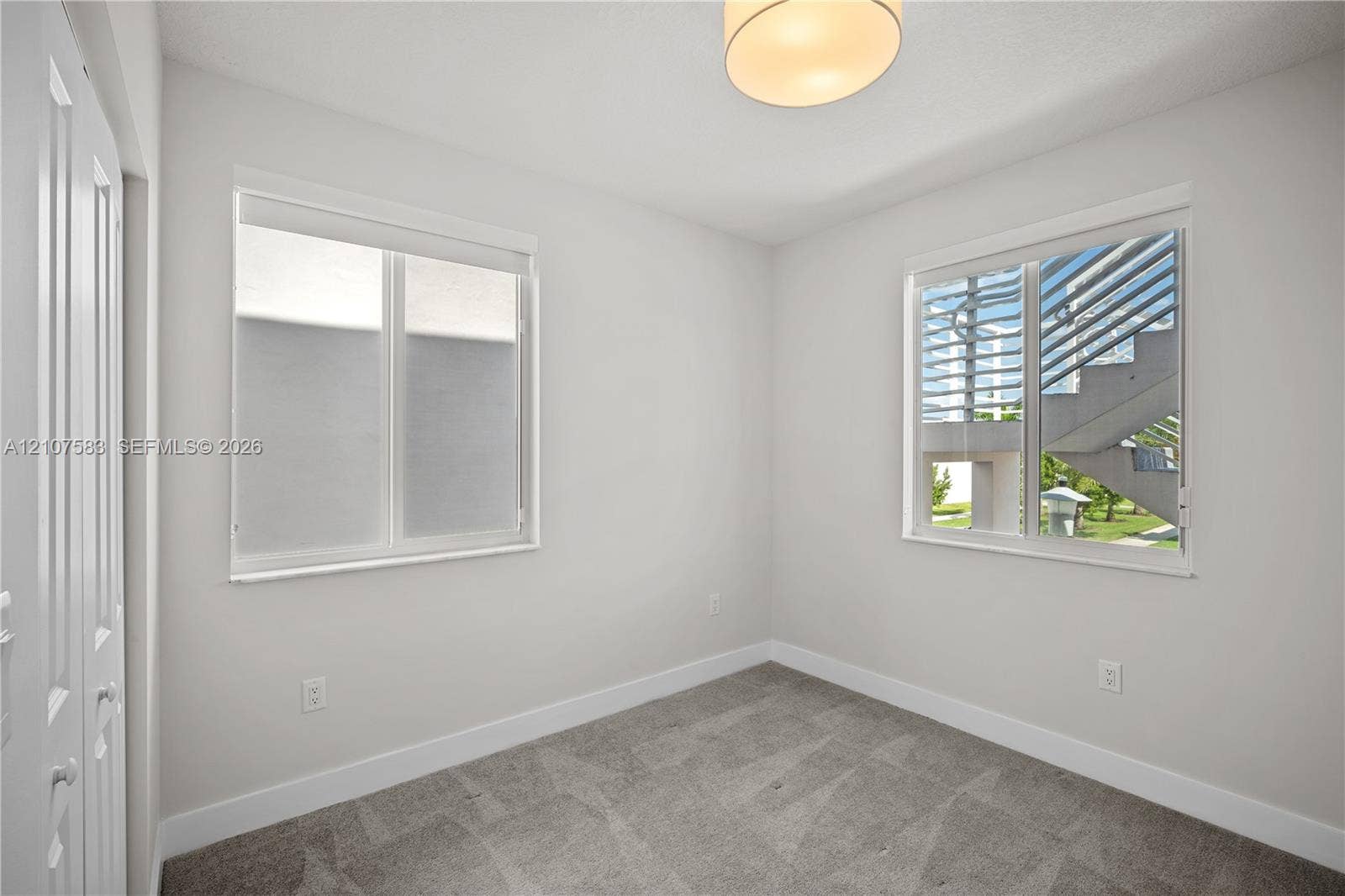 10270 NW 66th Street, #110, Doral, Doral, FL 33178 Neutral-toned interior featuring wall-to-wall carpeting, dual windows, a flush-mount drum ceiling light, and double-door closet storage