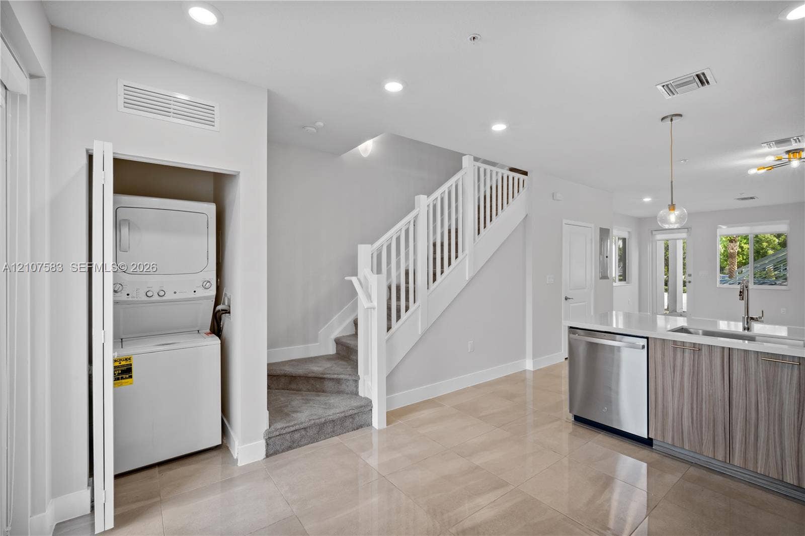 10270 NW 66th Street, #110, Doral, Doral, FL 33178 Neutral tile flooring, recessed lighting, white staircase with handrail, built-in laundry closet, and cabinetry with integrated stainless steel dishwasher