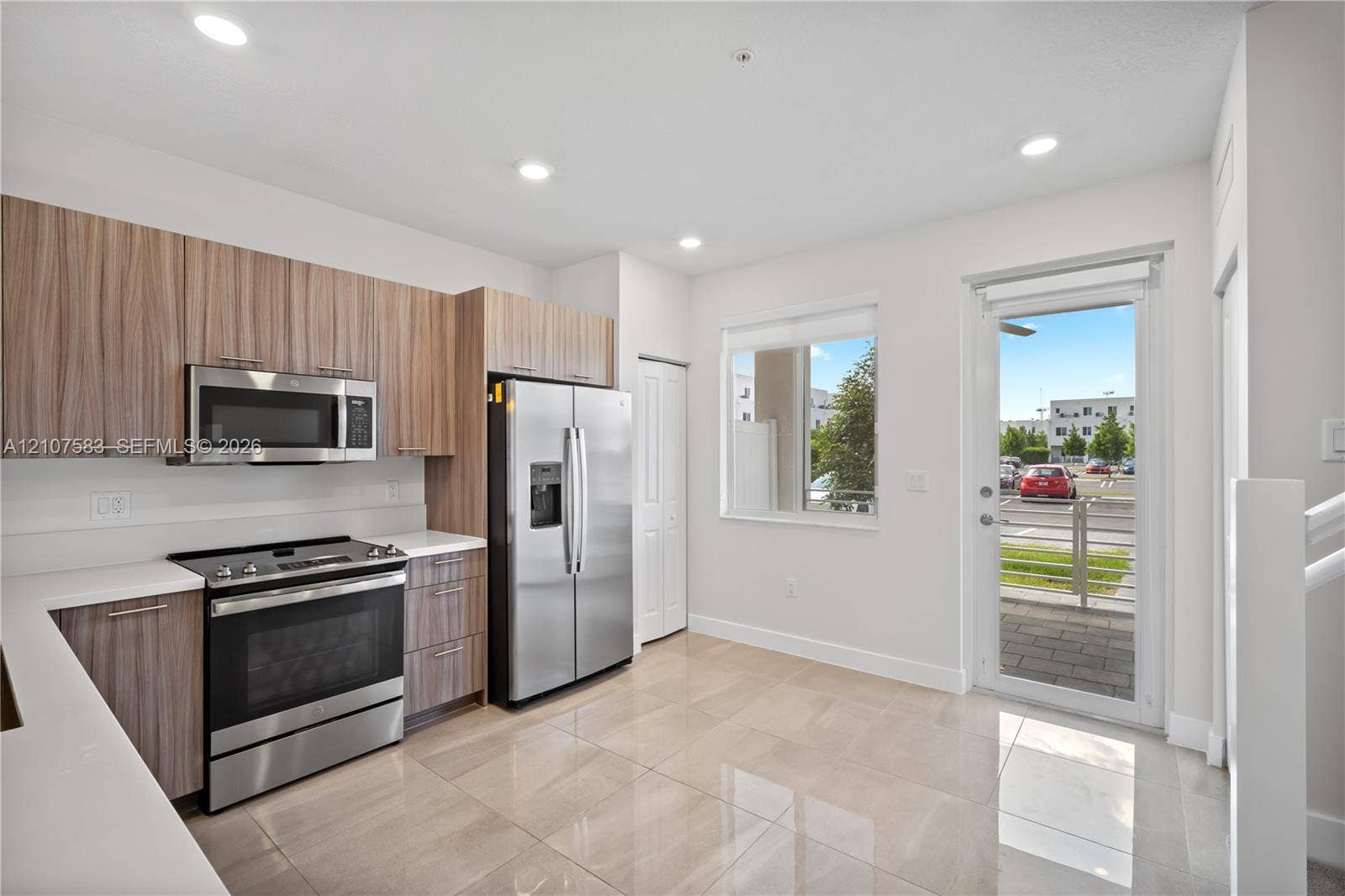 10270 NW 66th Street, #110, Doral, Doral, FL 33178 Kitchen featuring flat-panel wood-finish cabinetry, white countertops, stainless steel appliances, tile flooring, and a glass-panel door