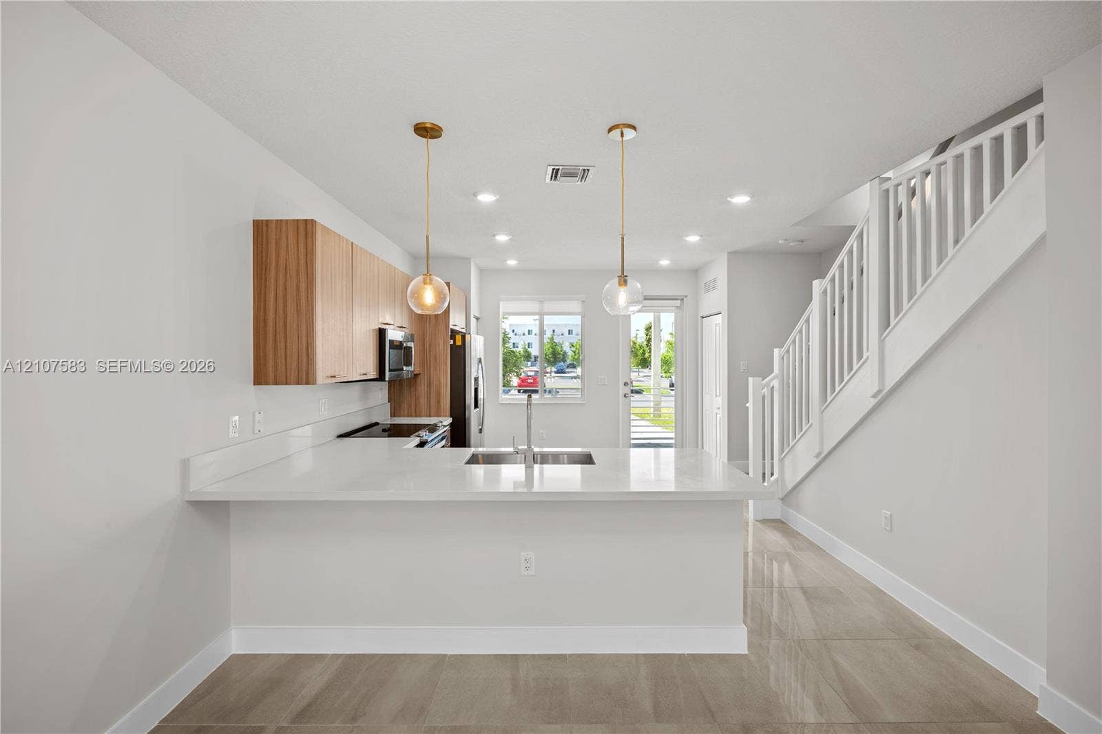 10270 NW 66th Street, #110, Doral, Doral, FL 33178 Kitchen featuring wood-finish cabinetry, quartz countertops, an undermount sink, pendant lighting, and polished tile flooring