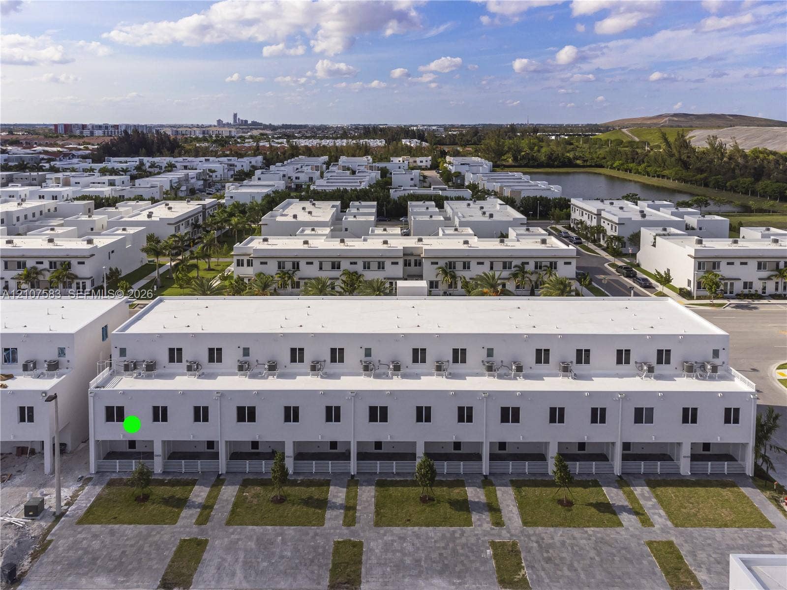 10270 NW 66th Street, #110, Doral, Doral, FL 33178 Multi-story townhouse exterior featuring a white stucco facade, flat roofline, paved ground-level patios, and dedicated lawn segments
