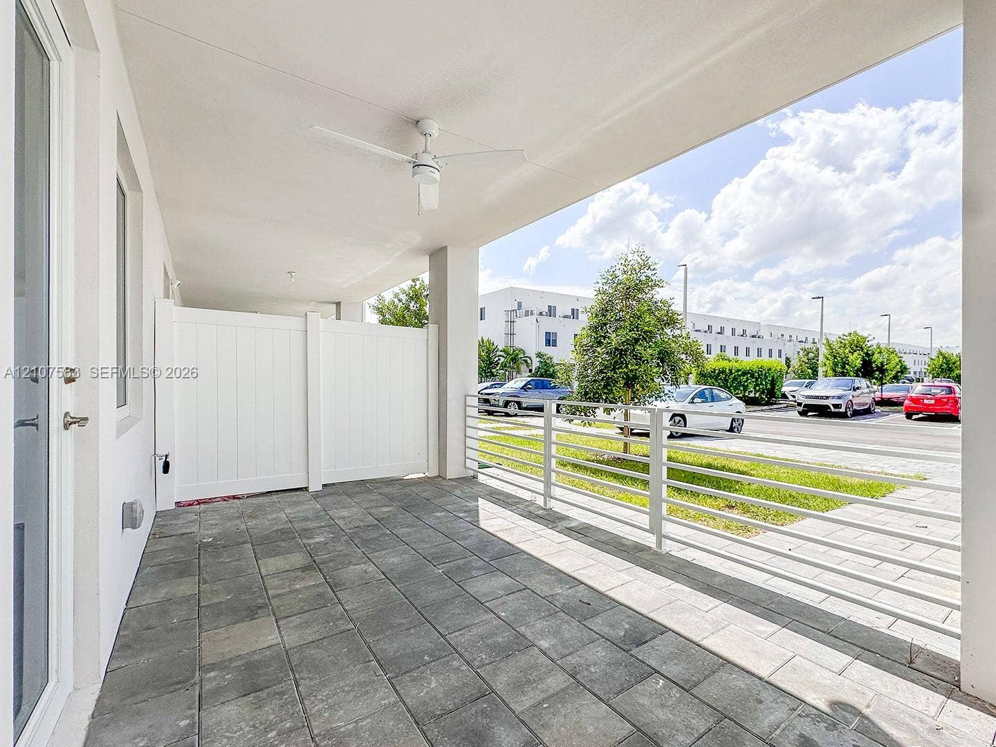 10270 NW 66th Street, #110, Doral, Doral, FL 33178 Covered outdoor patio featuring large-format tile flooring, a white vinyl privacy screen, and a ceiling-mounted fan
